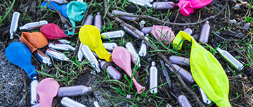 Des cartouches de gaz hilarant et des ballons dégonflés étalés dans l'herbe - MACSF