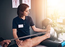 Une kinésithérapeute pratique des exercices de rééducation sur la jambe d'un patient - MACSF