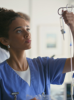 Une infirmière règle le débit d'une perfusion - MACSF
