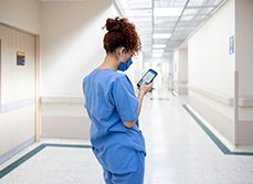 Une infirmière consultant son téléphone portable dans le couloir de l'hôpital - MACSF