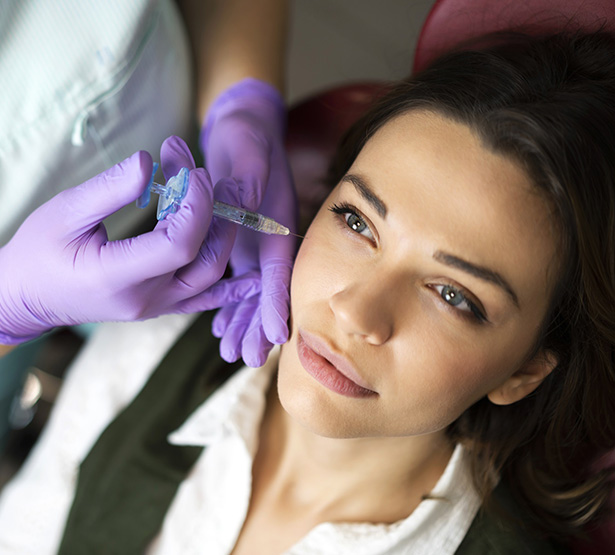 Main gantées procédant à une injection d'acide hyaluronique sur les pommettes d'une patiente - MACSF