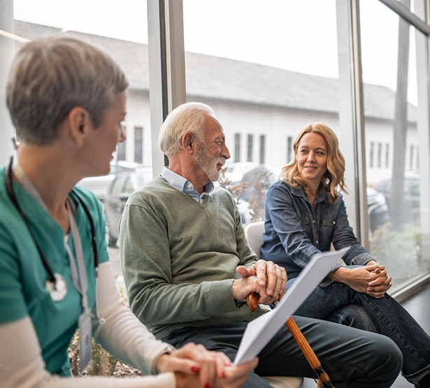 Une professionnelle de santé en discussion avec un patient âgé et sa fille à l'hôpital - MACSF