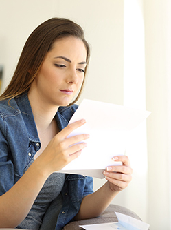Une femme assise lit un courrier - MACSF