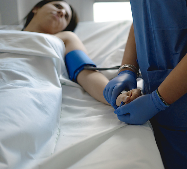 Une infirmière prend la tension d'une patiente alitée à l'hôpital - MACSF