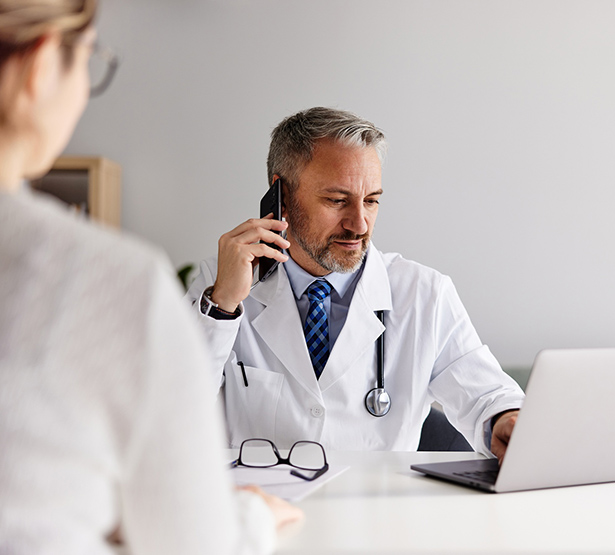 Un médecin répond au téléphone devant une patiente - MACSF