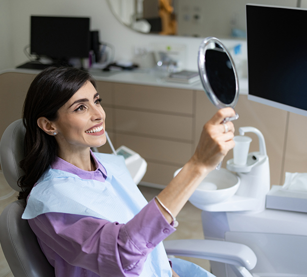 Une femme observe dans un miroir le résultat de ses soins en cabinet dentaire - MACSF