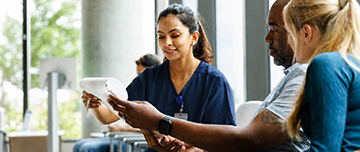 Une infirmière aide un patient à remplir un questionnaire en salle d'attente - MACSF