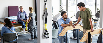 Des kinés discutent avec des patients dans une salle de rééducation - MACSF