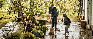 Un père et son enfant balayent une terrasse après une grosse pluie - MACSF