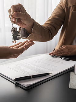 Une femme remet des clés à sa cliente au-dessus d'un contrat de bail - MACSF