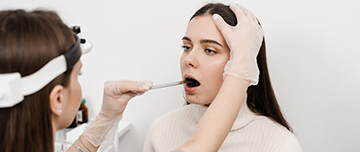 Une femme médecin examine la bouche d'une patiente - MACSF