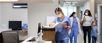 Une professionnelle de santé consulte un dossier sur le comptoir du service d'accueil de l'hopital - MACSF