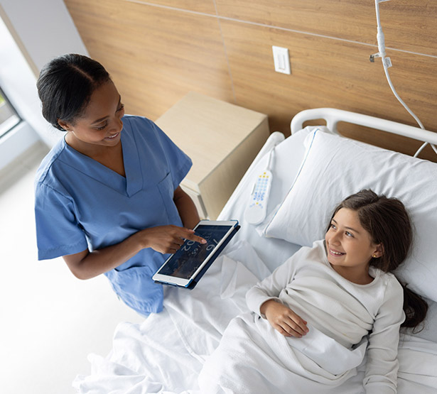 Une infirmière surveille les signes vitaux d’une fillette à l’aide d’une tablette numérique à l’hôpital - MACSF